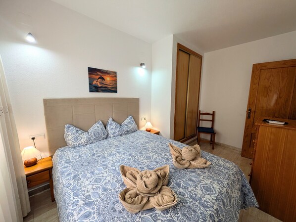 Une chambre à coucher avec un lit, une table de chevet, une armoire en bois et un tableau accroché au mur.