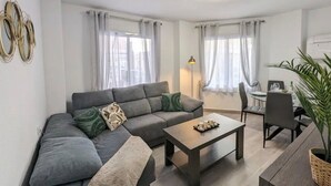 Una sala moderna con un sofá gris, una mesa de centro y una zona de comedor con una silla y mesa.