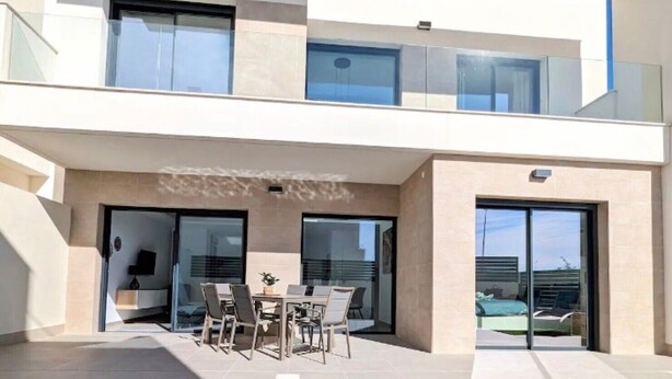 Une maison moderne à deux étages, dotée d’une piscine, d’un espace salon extérieur et de grandes fenêtres.