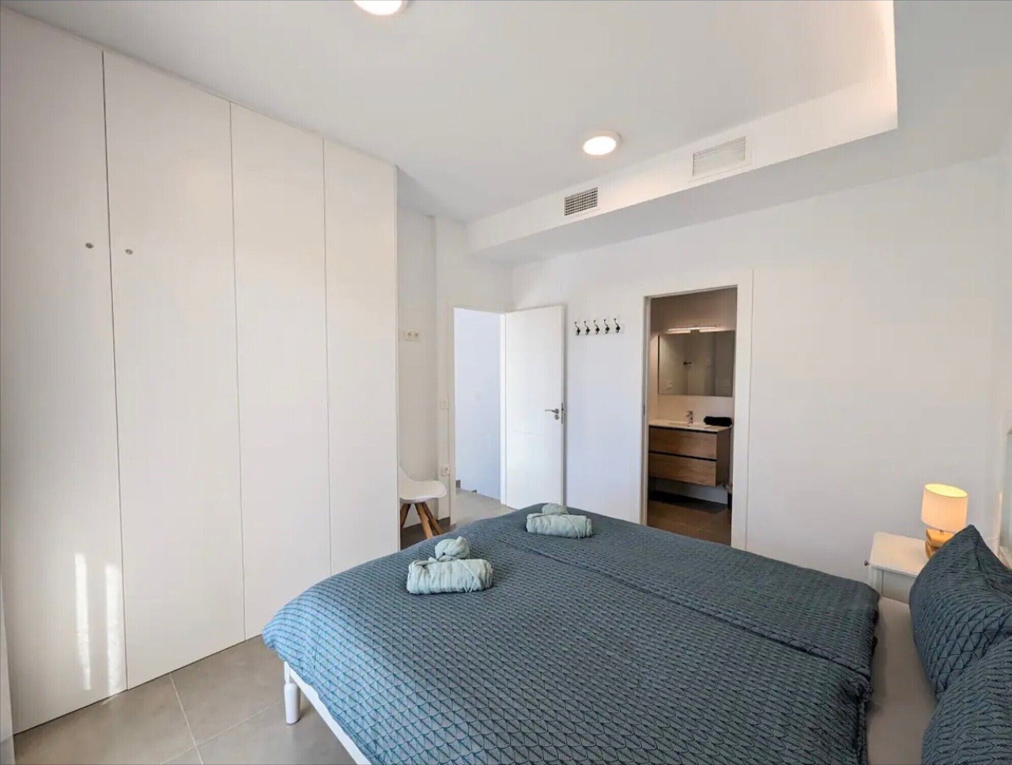 A bedroom with a bed, a wardrobe, a mirror, and a nightstand.