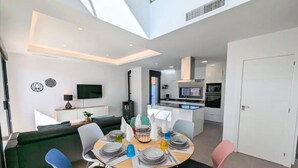 Un espace de vie moderne comprenant un coin repas, une cuisine et un téléviseur fixé au mur.