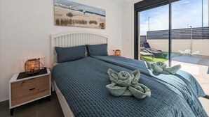 Une chambre à coucher avec un lit, une table de chevet, une lampe fixée au mur, une fenêtre et un tableau.