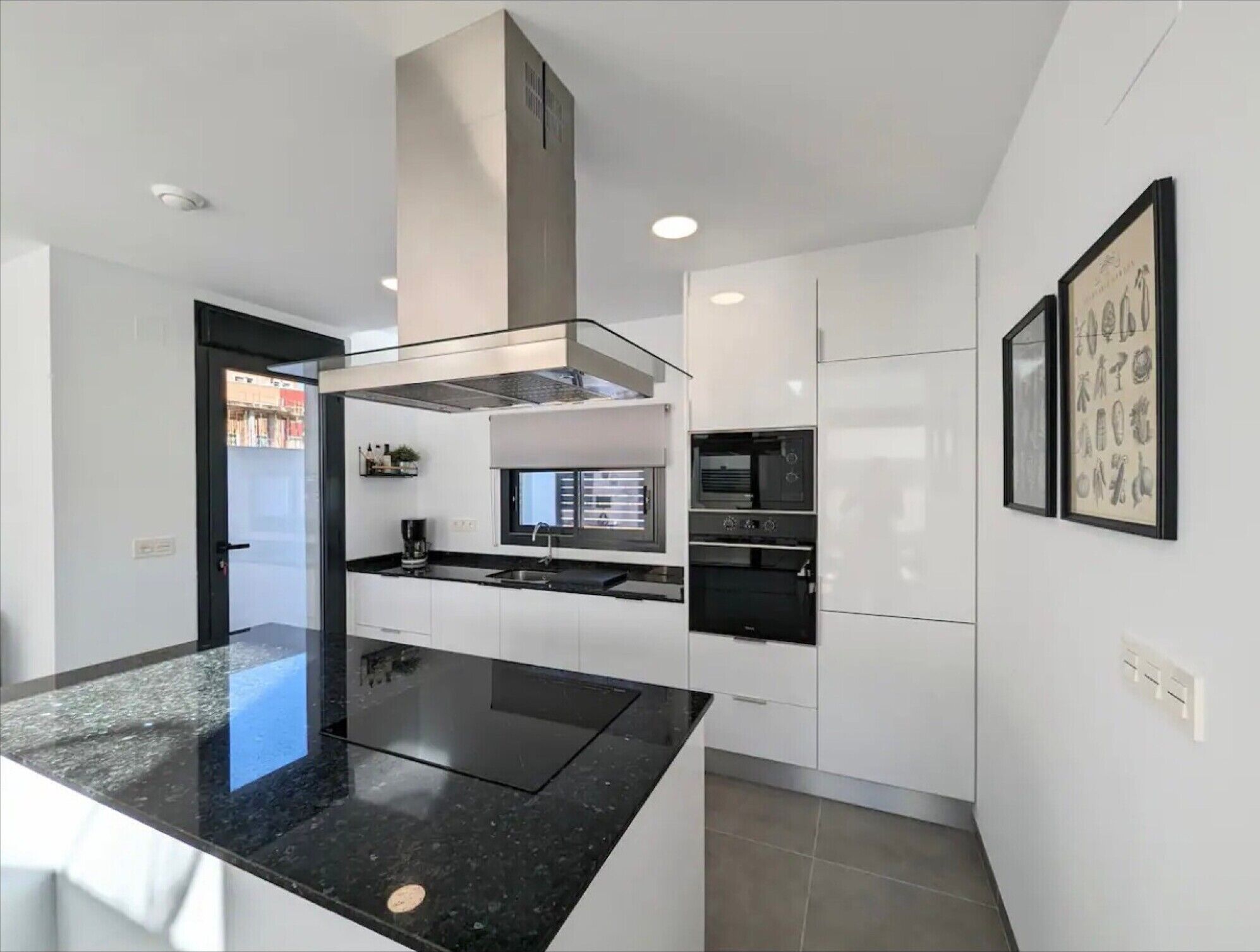A modern kitchen with a black granite countertop, white cabinetry, and a built-in oven.