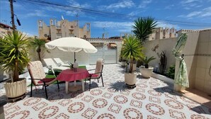 Un patio con suelo estampado, una mesa y sillas, y macetas con plantas.