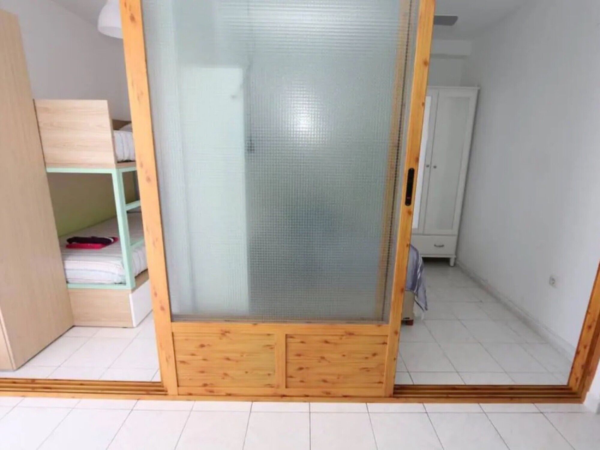 Une pièce dotée d’une porte-fenêtre coulissante, d’une armoire en bois et d’un meuble blanc.