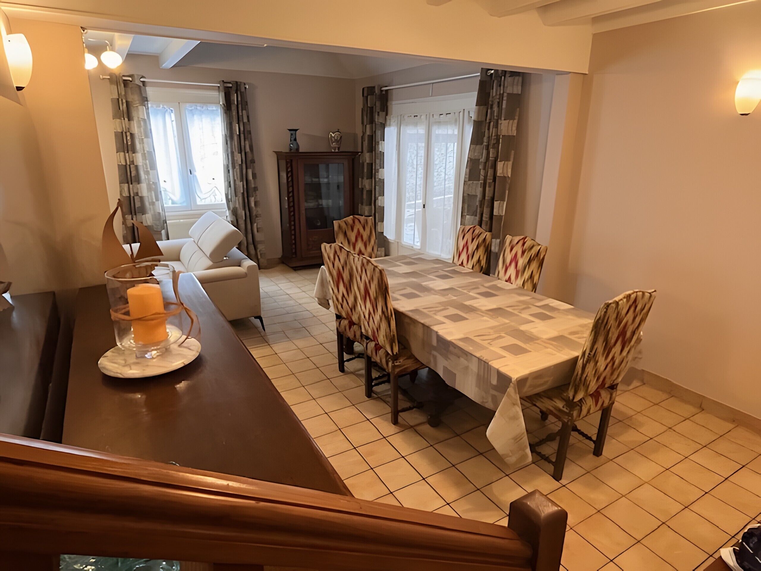 A dining area with a table, chairs, a sofa, and a cabinet.
