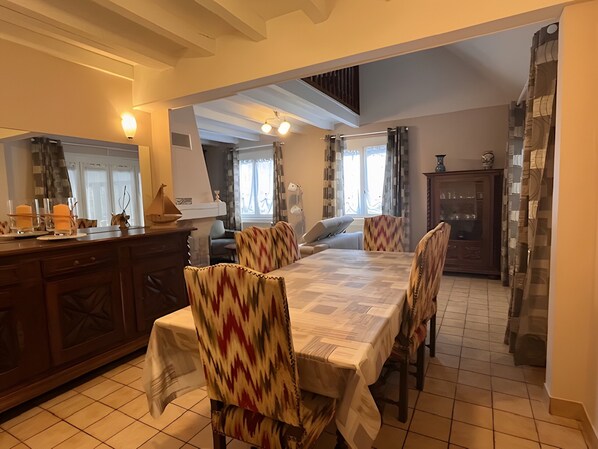 A dining area with a table, chairs, and a kitchen in the background.