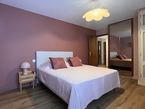 A bedroom with a bed, bedside lamp, and a wardrobe.