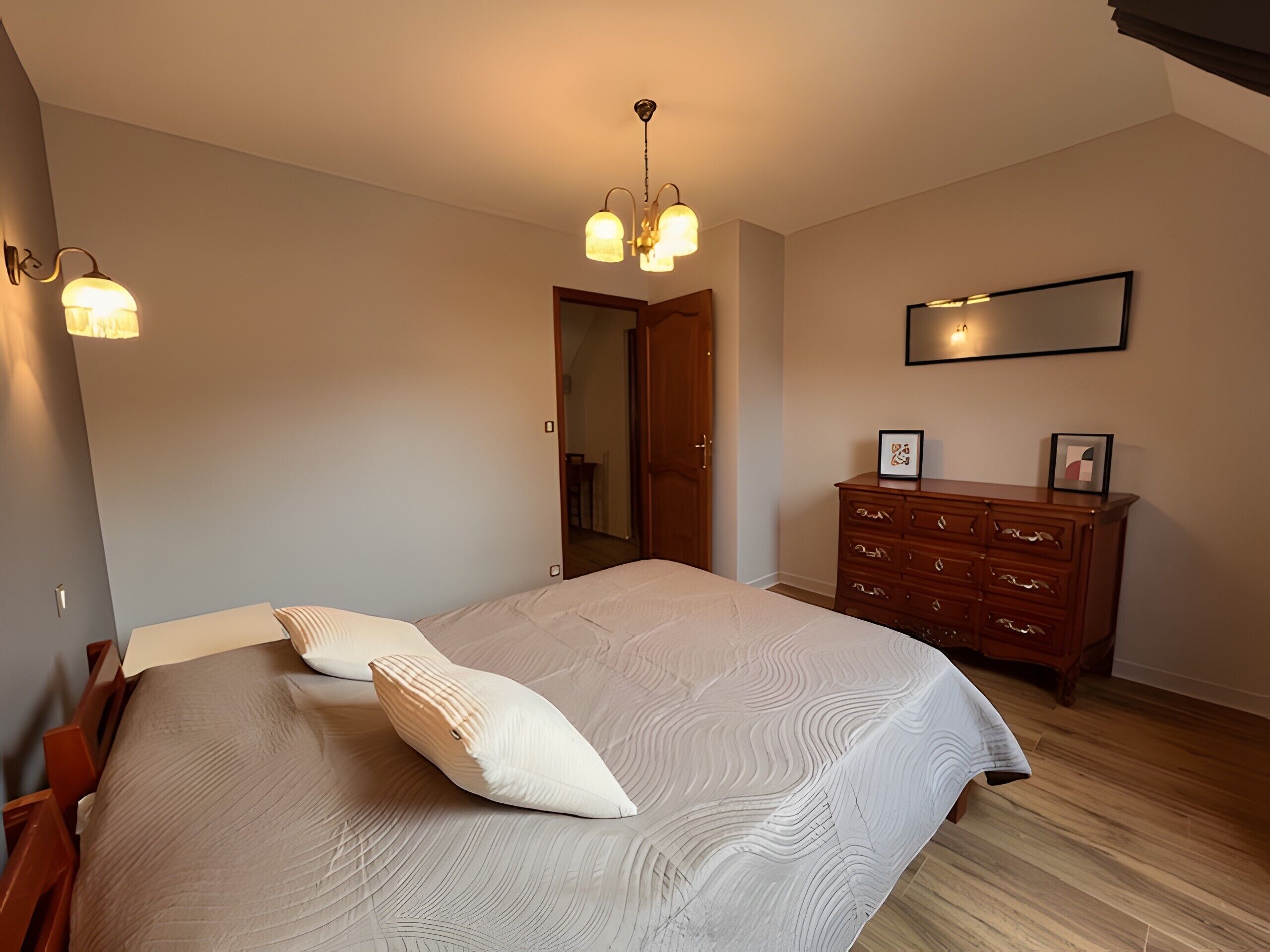 Une chambre à coucher avec un grand lit, une commode en bois et un miroir au mur.
