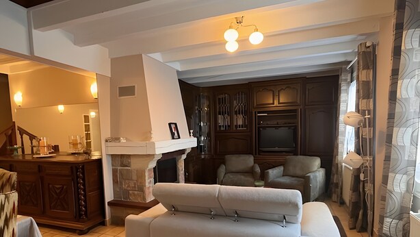 Una sala de estar con chimenea, un sofá, un televisor y un comedor con mesa y sillas.