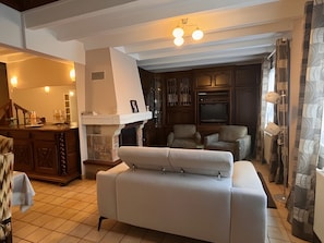 A living room with a fireplace, a sofa, a television, and a dining area with a table and chairs.