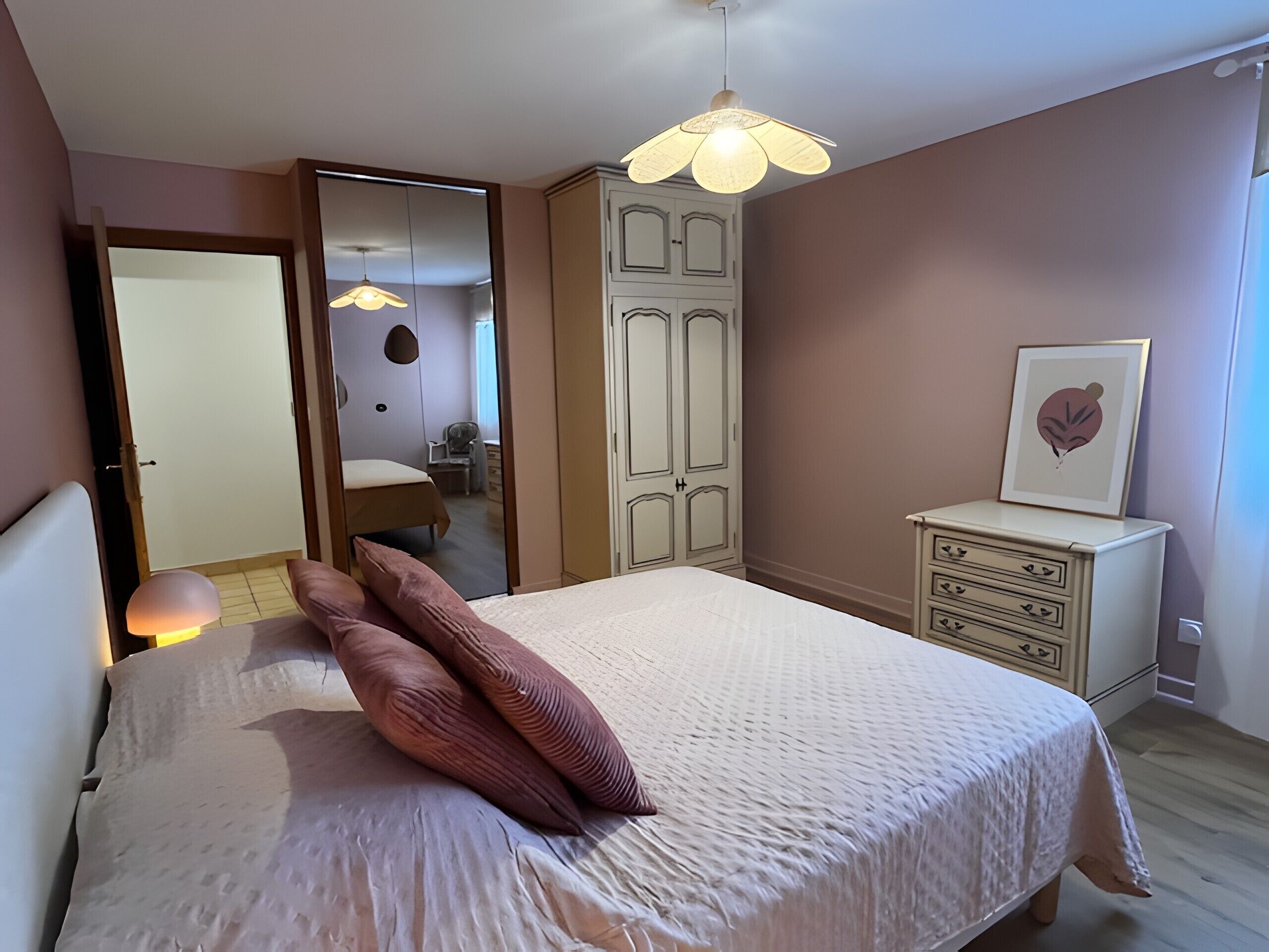 Une chambre à coucher comprenant un lit, une armoire, une table de chevet et un luminaire au plafond.