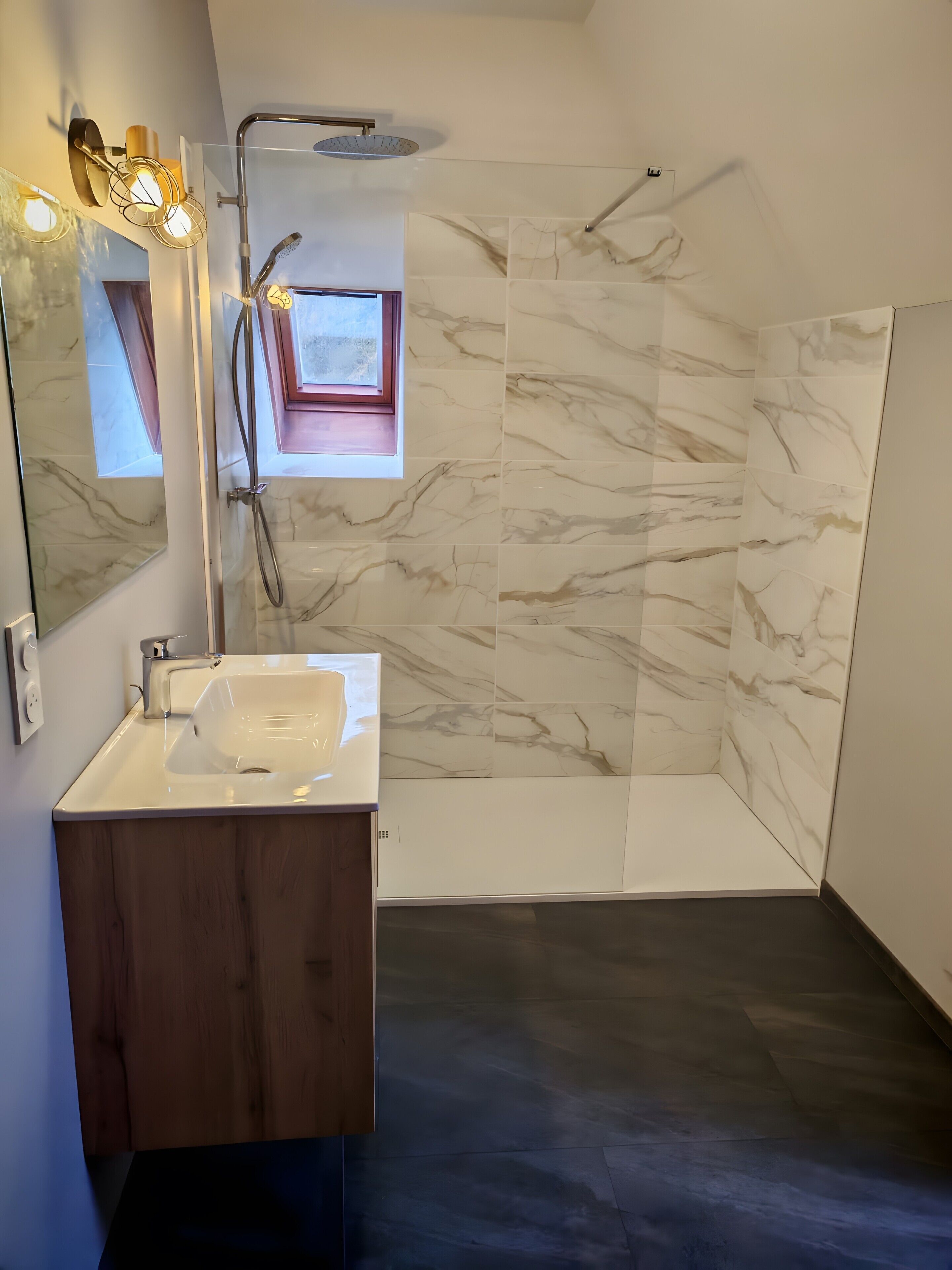 A modern bathroom with a marble shower, a wooden vanity, and a large mirror.