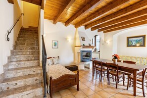 A bedroom with a wooden staircase, a bed, a wooden dining table with chairs, and a fireplace. - Apartment 'Appartamento Trilocale' with Shared Terrace, Shared Garden and Wi-Fi (Bardolino)