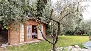 Eine Holzhütte mit Glastür, einem kleinen Tisch und einem Gartenbereich mit Steinen und Pflanzen.