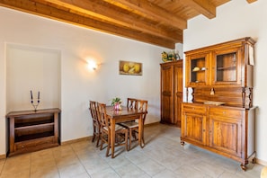 A dining area with a wooden table and chairs, a cabinet with glass doors, and a wall-mounted light fixture.