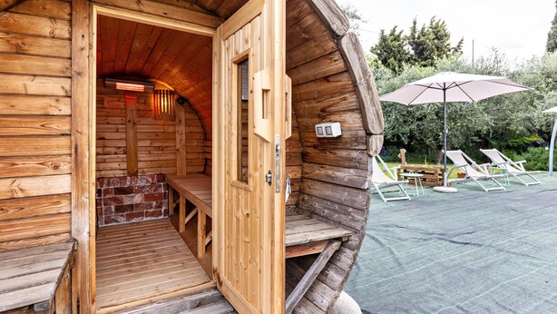 A wooden cabin with a wooden door, a bench, and an outdoor seating area with an umbrella. - Apartment 'Appartamento Bilocale' with Shared Terrace, Shared Garden and Wi-Fi (Bardolino)