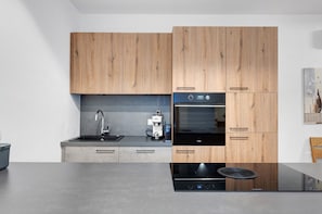 Une cuisine moderne avec des meubles en bois, un four encastré et une machine à café.