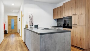 Eine moderne Küche mit Holzausstattung, einer zentralen Kochinsel und einem eingebauten Backofen.