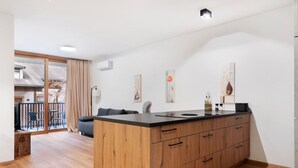 Een moderne keuken met een houten eiland, een zithoek met een bank en een balkon met uitzicht.