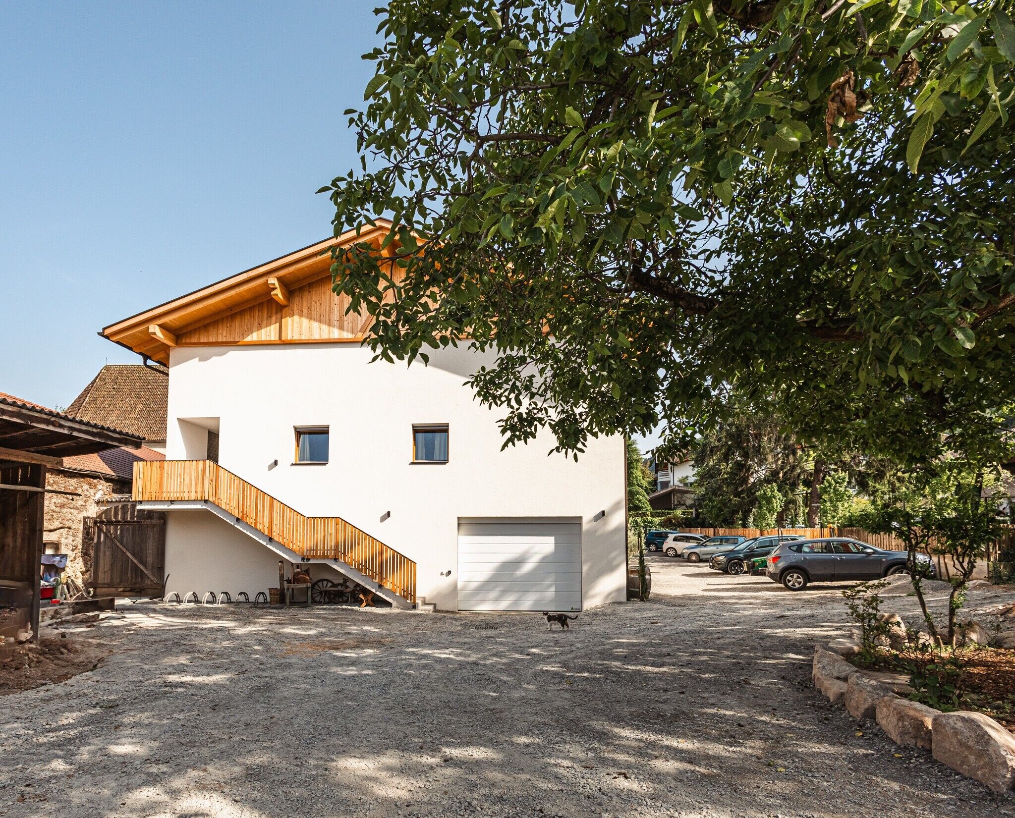 Un bâtiment à deux étages avec un escalier en bois, un garage et une allée gravillonnée.