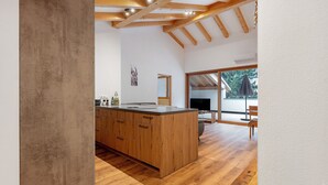Une cuisine moderne avec des meubles en bois, un grand îlot central et un coin repas comprenant une table et des chaises.