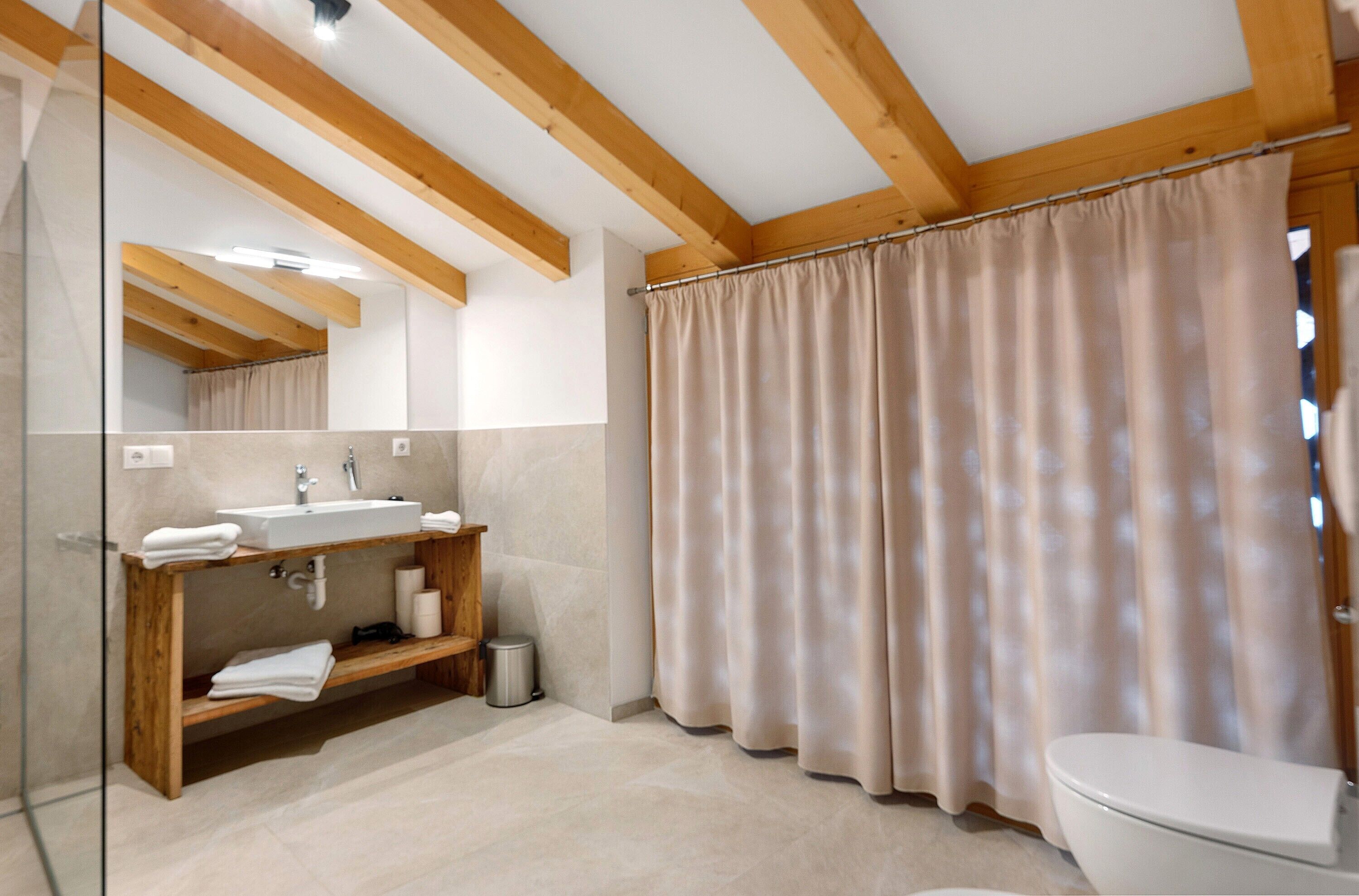 A bathroom with a wooden vanity, a sink, a toilet, and a shower curtain.