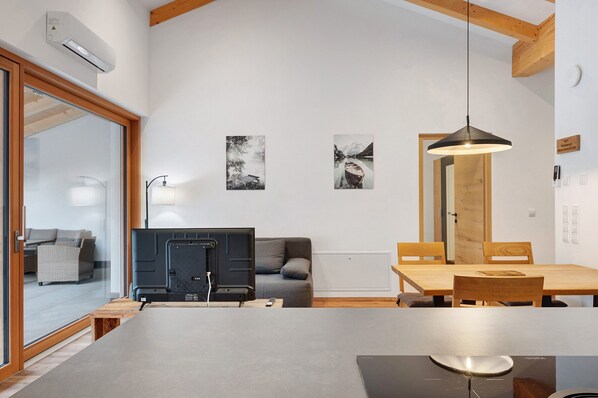Una sala de estar moderna con televisor de pantalla plana, una mesa de comedor de madera y dos obras de arte enmarcadas en la pared.