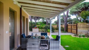 An outdoor patio with wicker furniture, a stone floor, and a view of the surrounding garden and trees. - Casale Lorenzo - Apartment 2 with Private Terrace, Shared Garden and Air Conditioning (Orbetello)