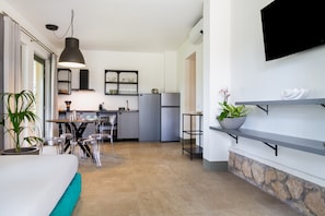 Une cuisine moderne avec un coin repas, un téléviseur fixé au mur et un mur d’accent en pierre.
