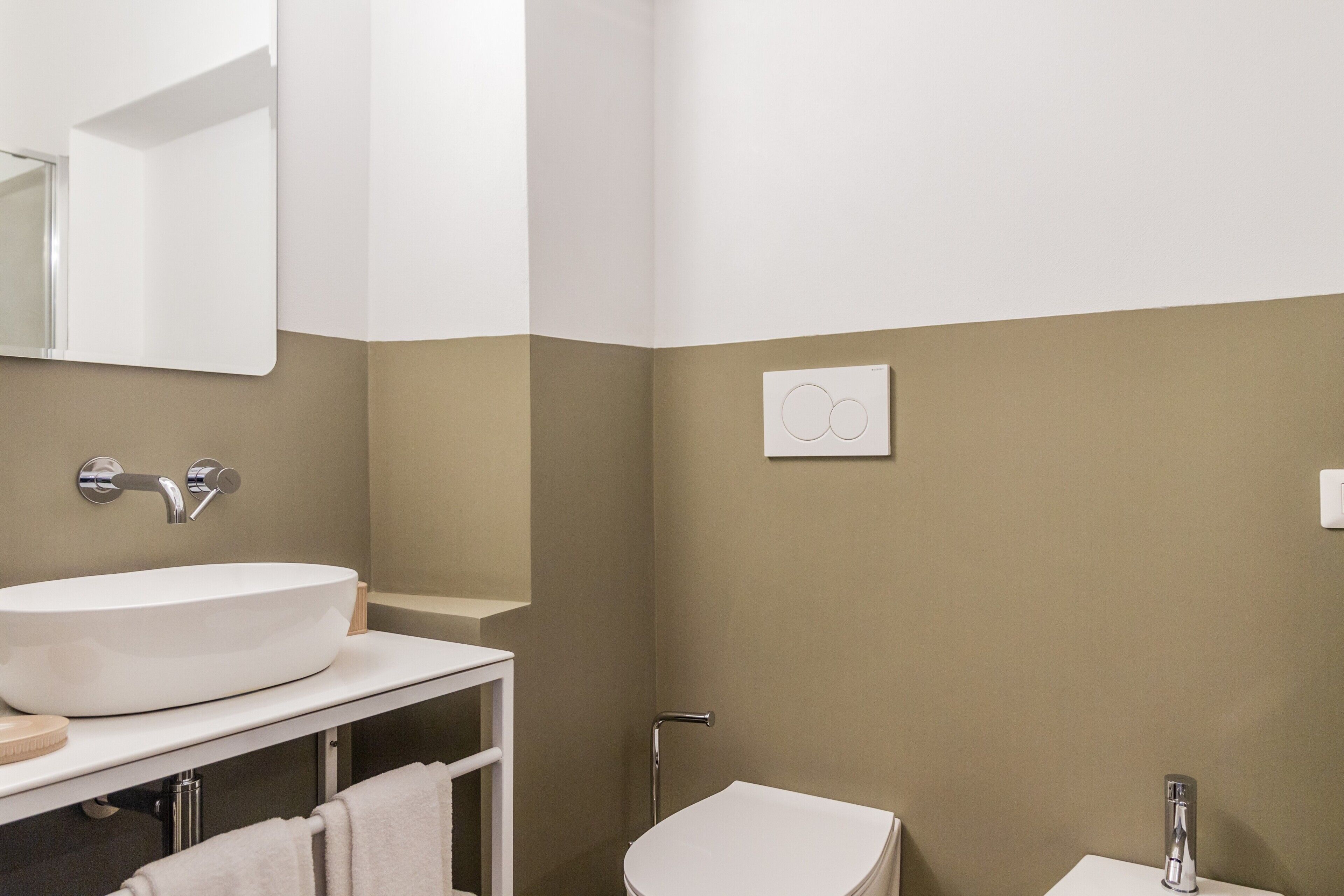 A bathroom with a large white sink, a mirror, a towel rack, and a toilet.