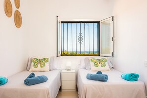 Ein Zimmer mit zwei Betten, einem Fenster mit Blick und einem Nachttisch mit Lampe.