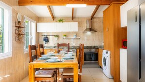 Una cocina con zona de comedor, vigas de madera, lavadora y armarios.