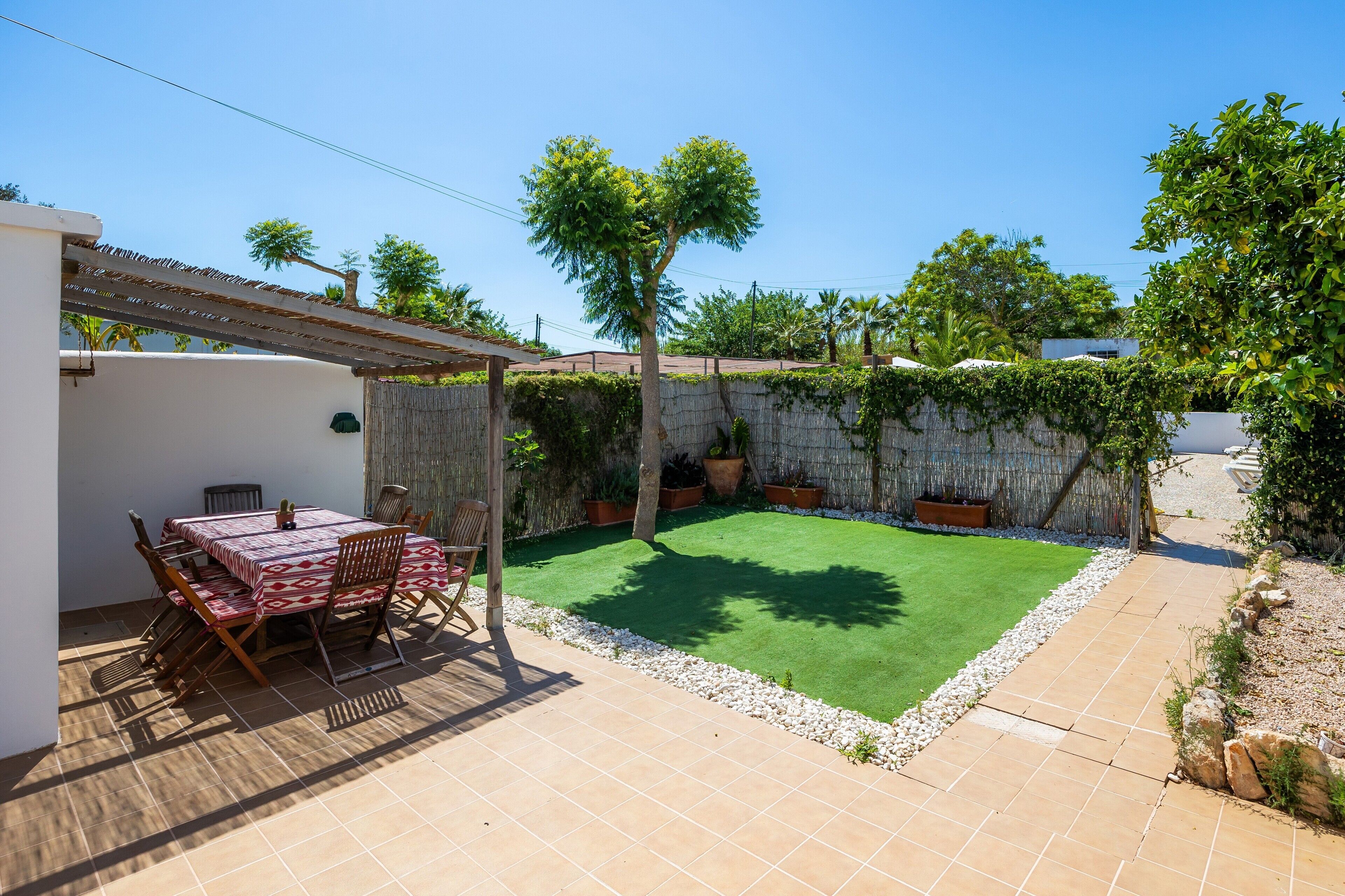 A patio with a table and chairs, a small lawn, and a stone wall.