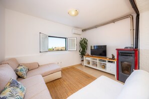 Ein Wohnzimmer mit einer Couch, einem Fernseher, einem Kamin und einem Fenster mit Blick.