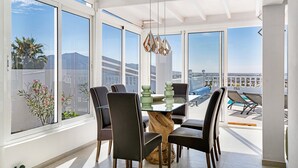 Un coin repas avec une table en verre, des chaises et un luminaire suspendu.