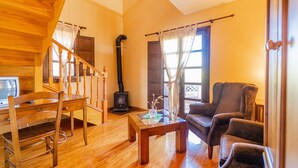 Una sala de estar acogedora con piso de madera, una chimenea, un sofá, una mesa de centro y un televisor.