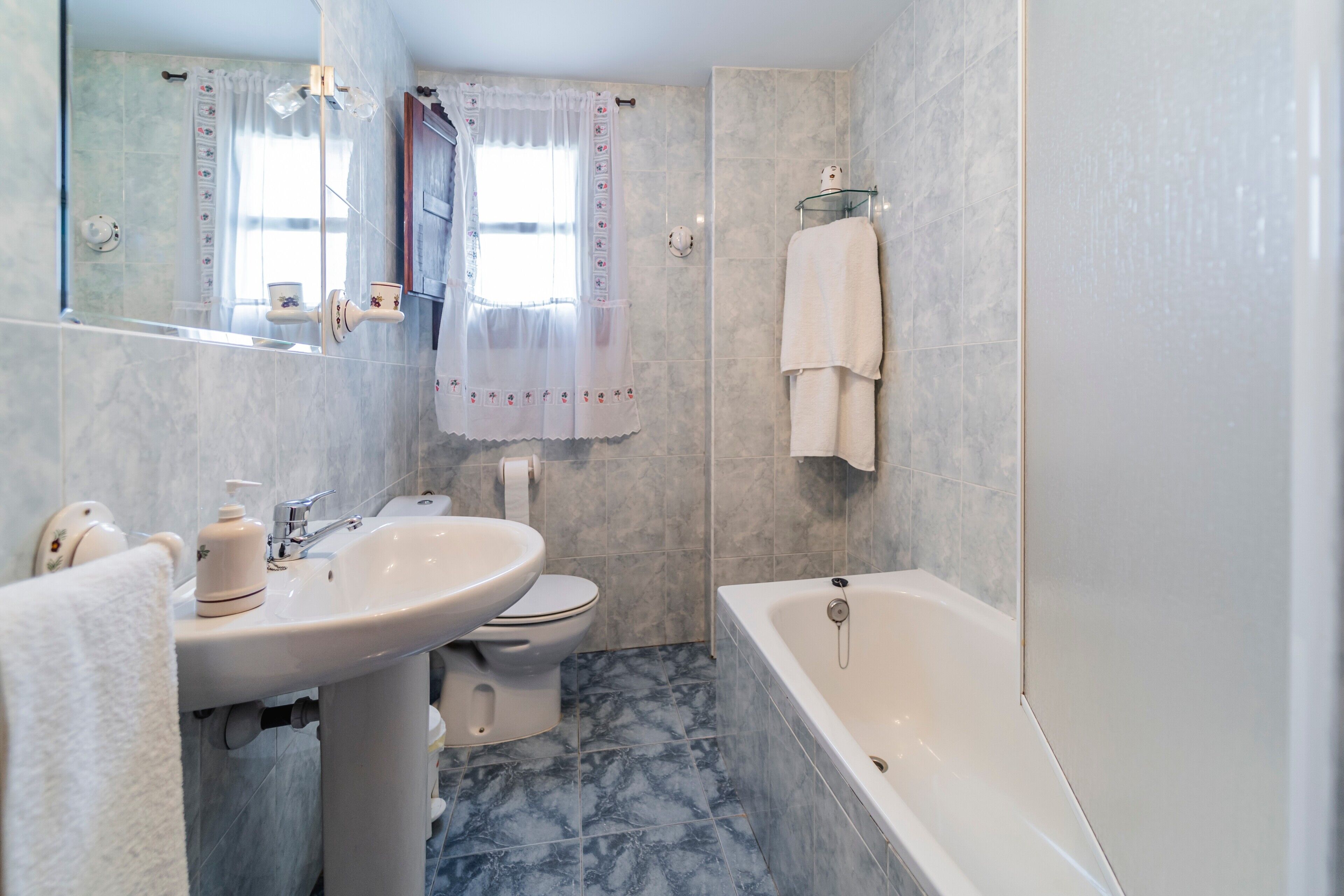 Un baño con lavamanos, inodoro, bañera y espejo.