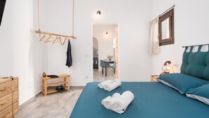A bedroom with a bed, a wooden dresser, a bench, and a hanging clothes rack. - Apartment 'S' Istancu Vetzu' with Mountain View, Wi-Fi and Air Conditioning (Irgoli)