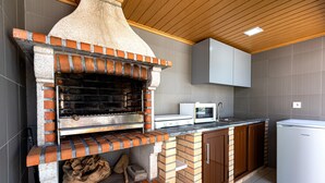 A kitchen with a brick oven, a microwave, and a refrigerator.