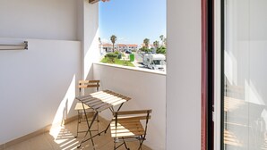 Ein Balkon mit Blick auf eine Straße, einem Wäscheständer und zwei Holzstühlen.