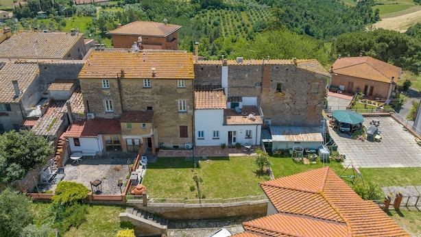 A traditional building with a courtyard, surrounded by lush green fields and hills.