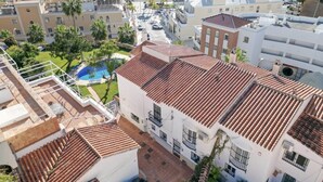 Een kusthotel met terracotta dakpannen, een zwembad en uitzicht op het strand.