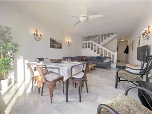 Un comedor con una mesa y sillas, un sofá, una escalera y un televisor.