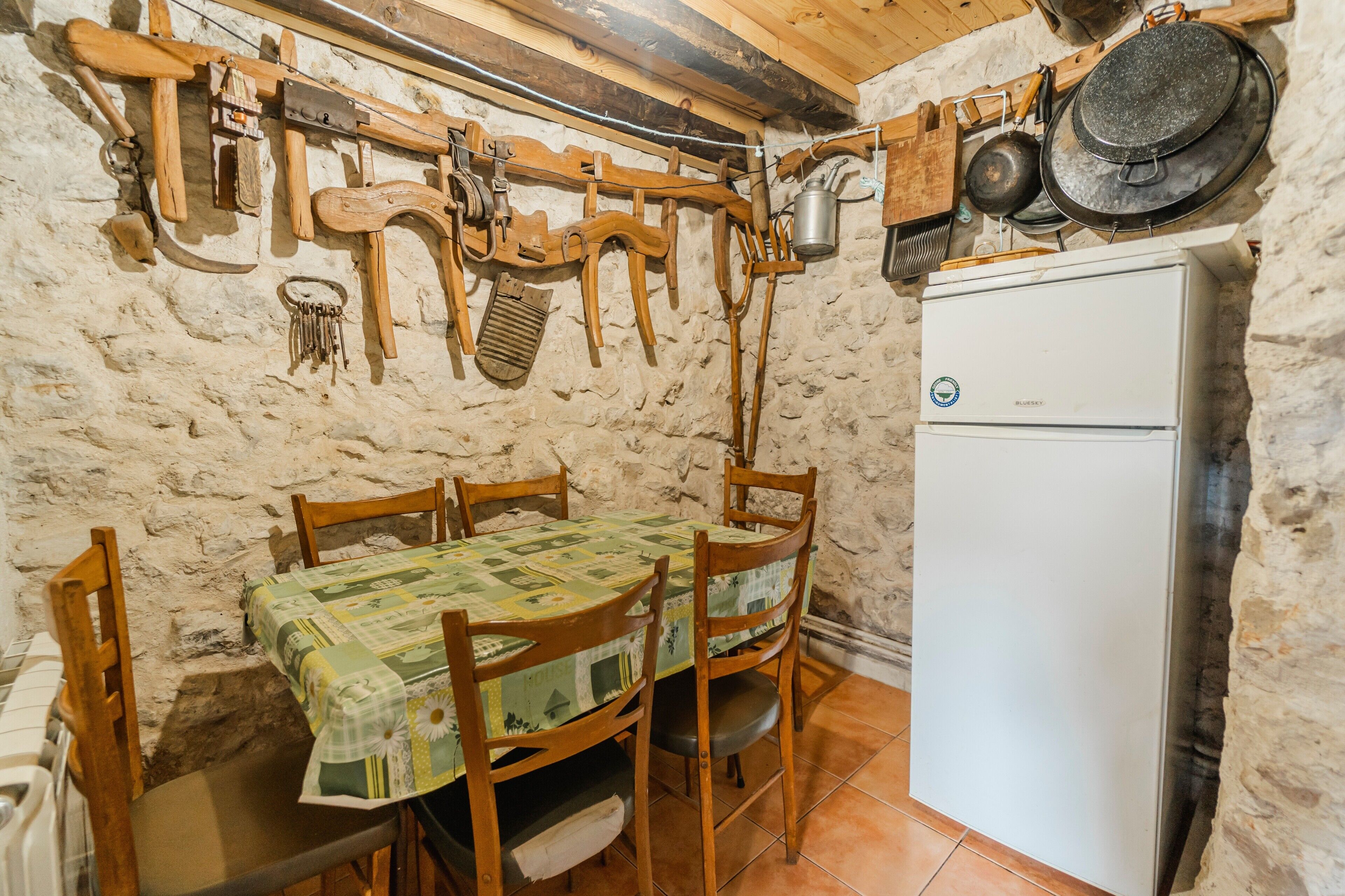 Une cuisine rustique avec des murs en pierre, des meubles en bois et un réfrigérateur blanc.
