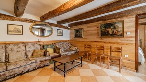 Een kamer met een houten plafond, een bank, een tafel en stoelen.