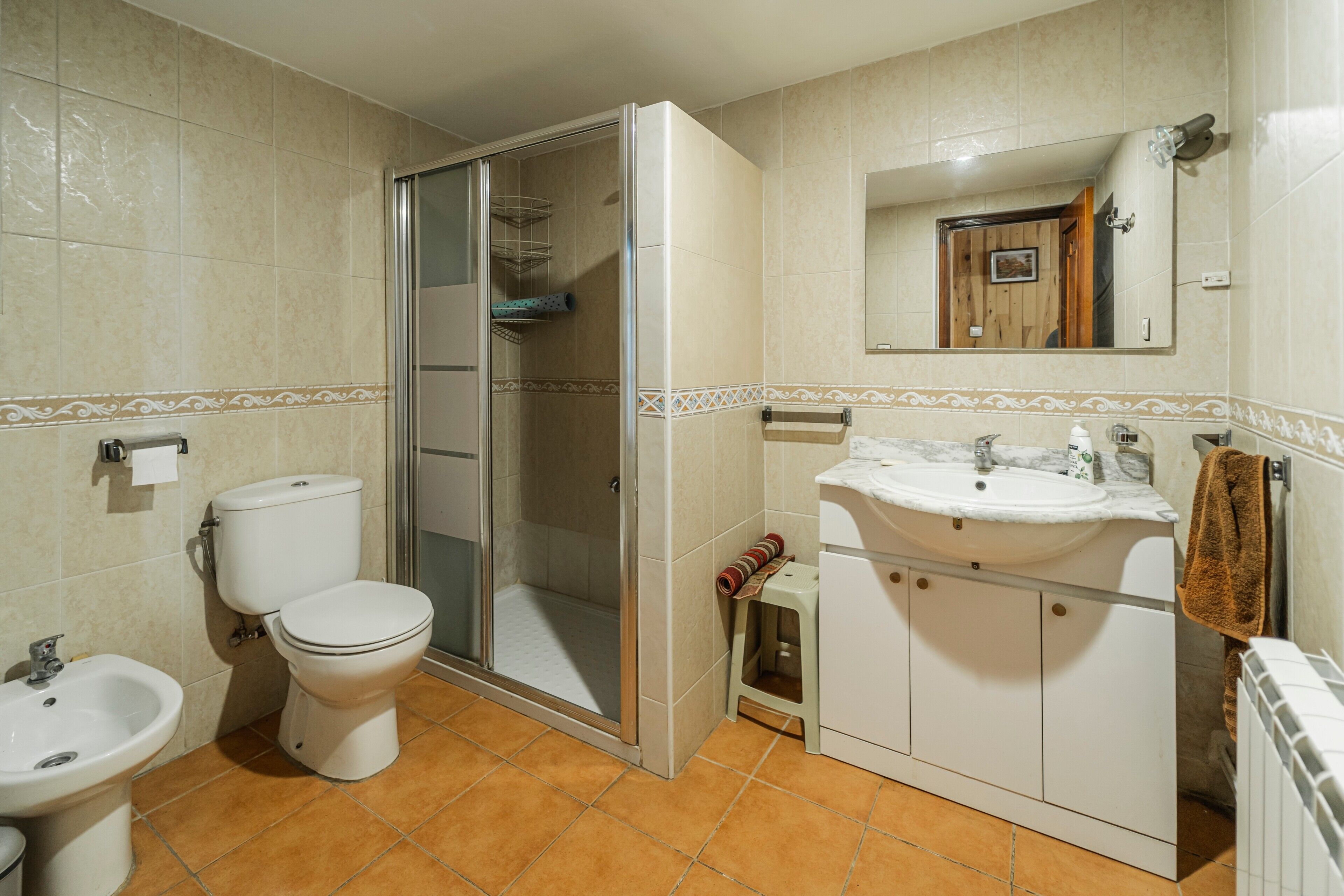 Ein Badezimmer mit Toilette, Bidet, Dusche, Waschbecken und Spiegel.