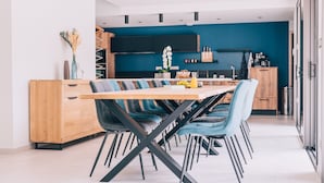 A modern kitchen with a blue accent wall, a wooden dining table, and blue upholstered chairs.