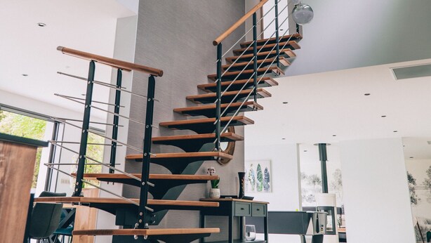 A modern interior with a spiral staircase, wooden benches, and hanging spherical lights.