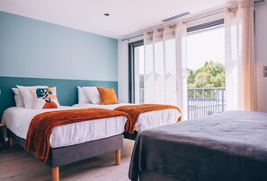 A hotel room with two beds, a balcony, and a large window.